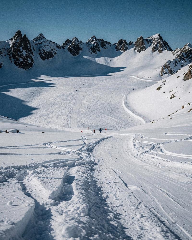 Alpine bowl with groomed pistes below a ridgeline